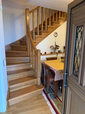 Una escalera de madera conduce a un comedor con una mesa y sillas.