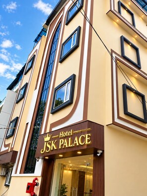 Fachada de un hotel con un letrero llamativo que dice 'J&K Palace Hotel'.