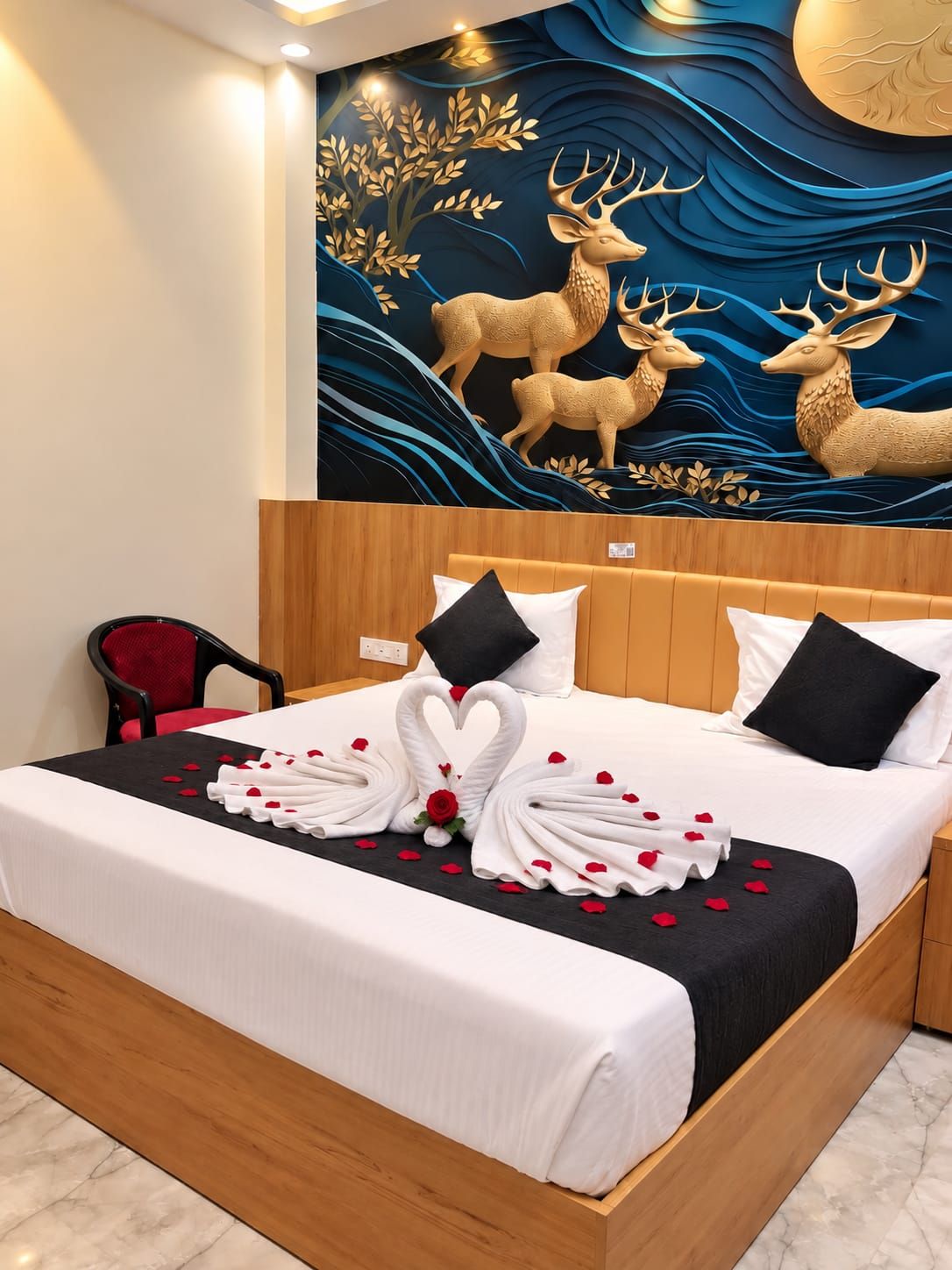 A hotel room with a bed, a red chair, and a wall mural of deer.