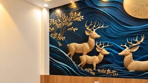 Habitación de hotel con cama, una silla roja y un mural de ciervos.