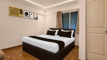 Un dormitorio con cama, ventana con cortinas, puerta y cuadros en la pared.