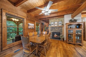 A wooden interior with a dining table, chairs, a fireplace, and a cabinet. - Peaceful Foscoe Retreat with Hot Tub (Boone)