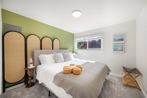 A neatly arranged bedroom with a bed, bedside tables, and a window with a view. - Modern 2BR Queen Anne Condo, Walk to Downtown (Seattle)