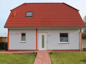 A single-story building with a red-tiled roof, a white exterior, and a small front entrance. - Holiday Home Columbine (Rerik)