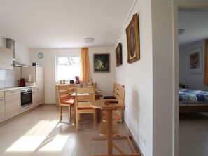 A compact living space with a kitchenette, dining area, and a bed. - Holiday Home Columbine (Rerik)