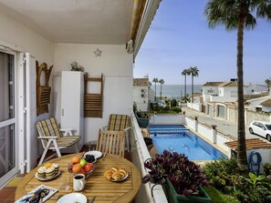 A balcony with a pool, outdoor seating, and a view of the sea. - Sunstay Flat Cortijera Mijas (Mijas)