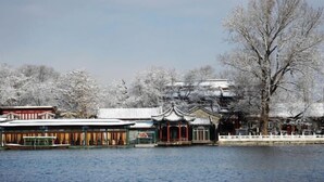 Ein traditionelles Gebäude mit Ziegeldach, ein großer Baum davor und dahinter ein Gewässer.
