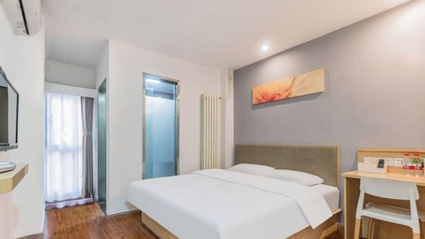 Ein Hotelzimmer mit Bett, Schreibtisch, Stuhl, Fernseher und einer Badezimmertür.