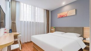 Ein Hotelzimmer mit Bett, Schreibtisch, Stuhl, Nachttisch und einem Bild an der Wand.