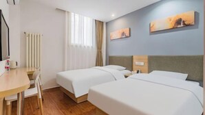 Ein Hotelzimmer mit zwei Betten, einem Schreibtisch, einem Stuhl und einer Heizung.