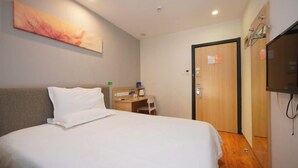 Ein Hotelzimmer mit Bett, Schreibtisch, Fernseher und einer Tür.
