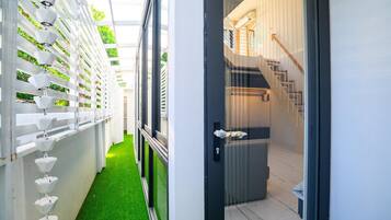 A modern interior with a staircase, a hallway with green artificial grass, and a wall with multiple levels of white planters.