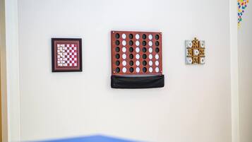 Een muur met drie ingelijste items: een schaakbord, een kruisje-tjes bord en een spelbord met X'en en O's.