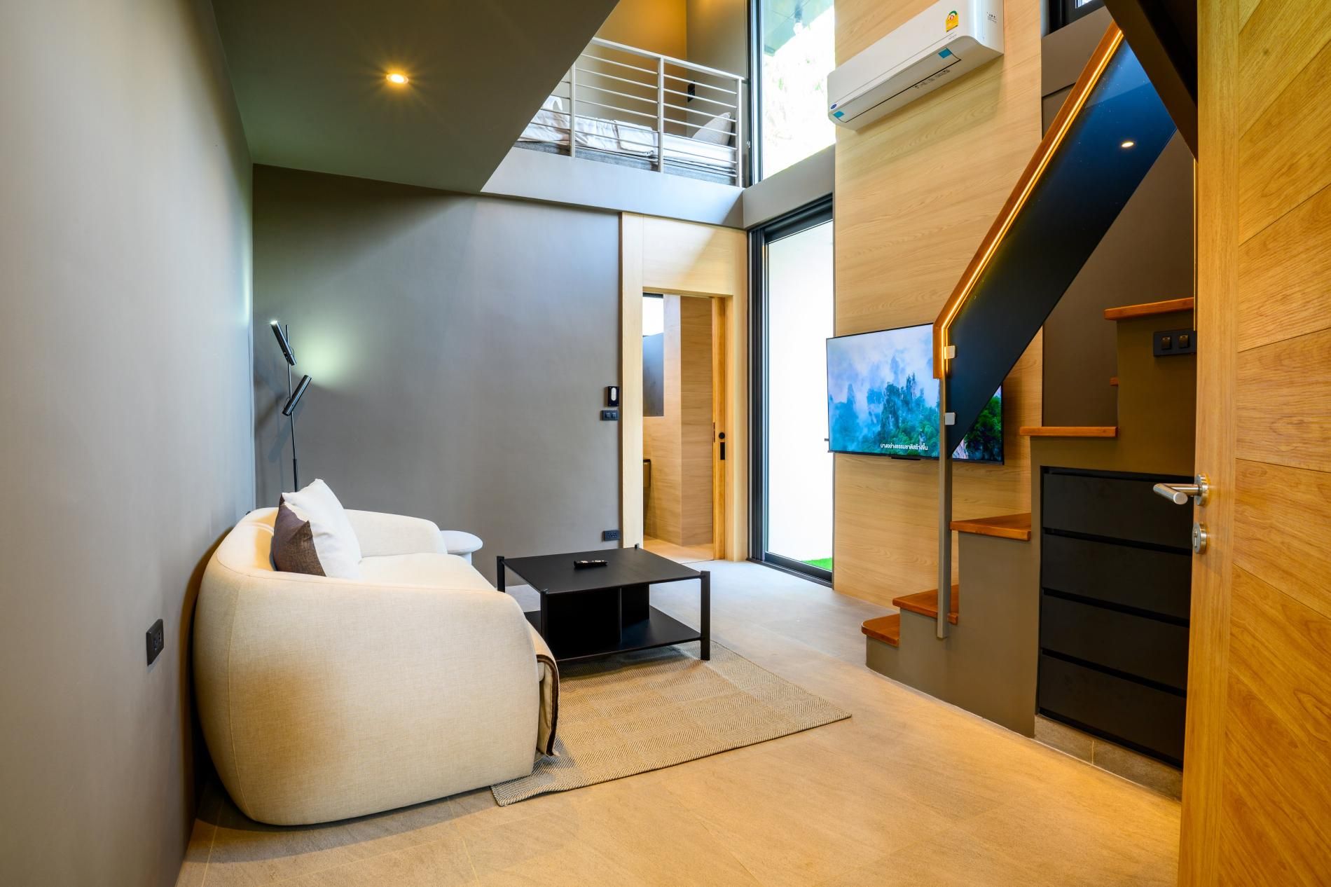 A modern living room with a sofa, a coffee table, and a TV mounted on the wall.