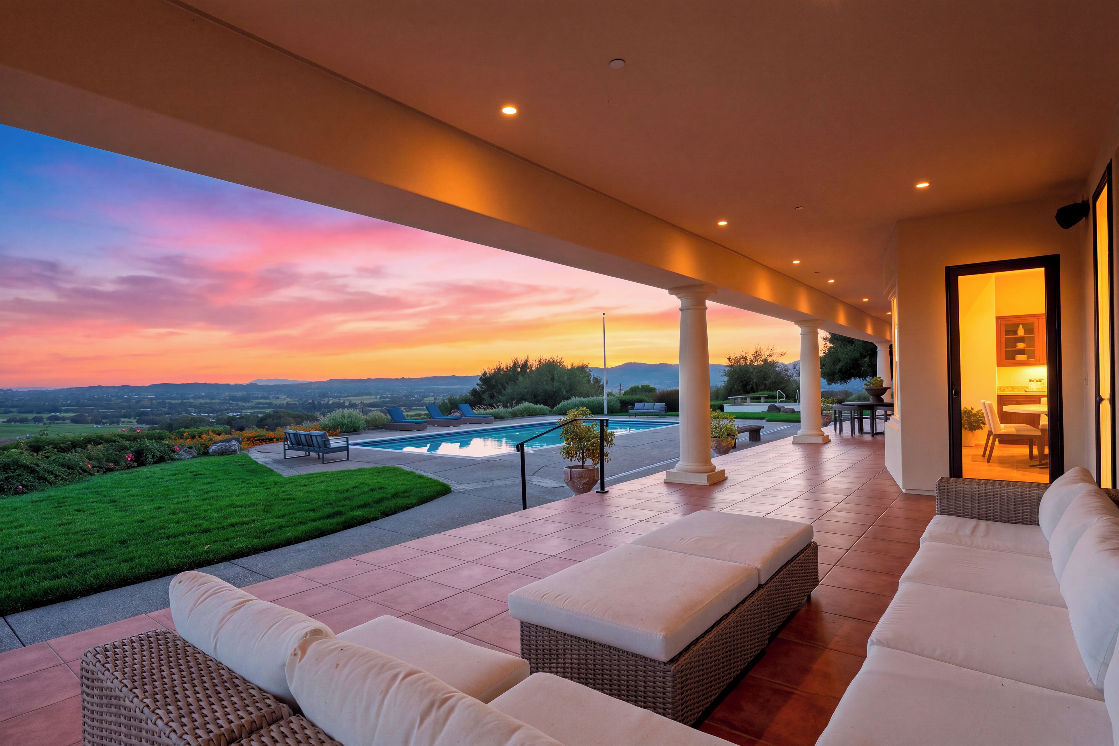 A covered outdoor area with a pool, seating, and a view of the landscape.