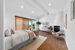 Een slaapkamer met een groot bed, een open haard en uitzicht op de omgeving.