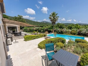 A poolside area with a barbecue, seating, and a view of the pool. - Holiday Home in Grimaud With Swimming Pool (Grimaud)