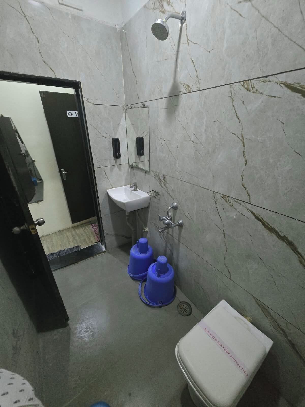 A bathroom with a white sink, a mirror, a shower, and a toilet.