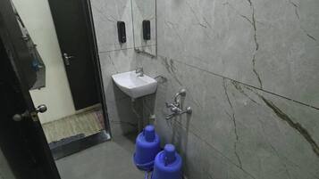 A bathroom with a white sink, a mirror, a shower, and a toilet.