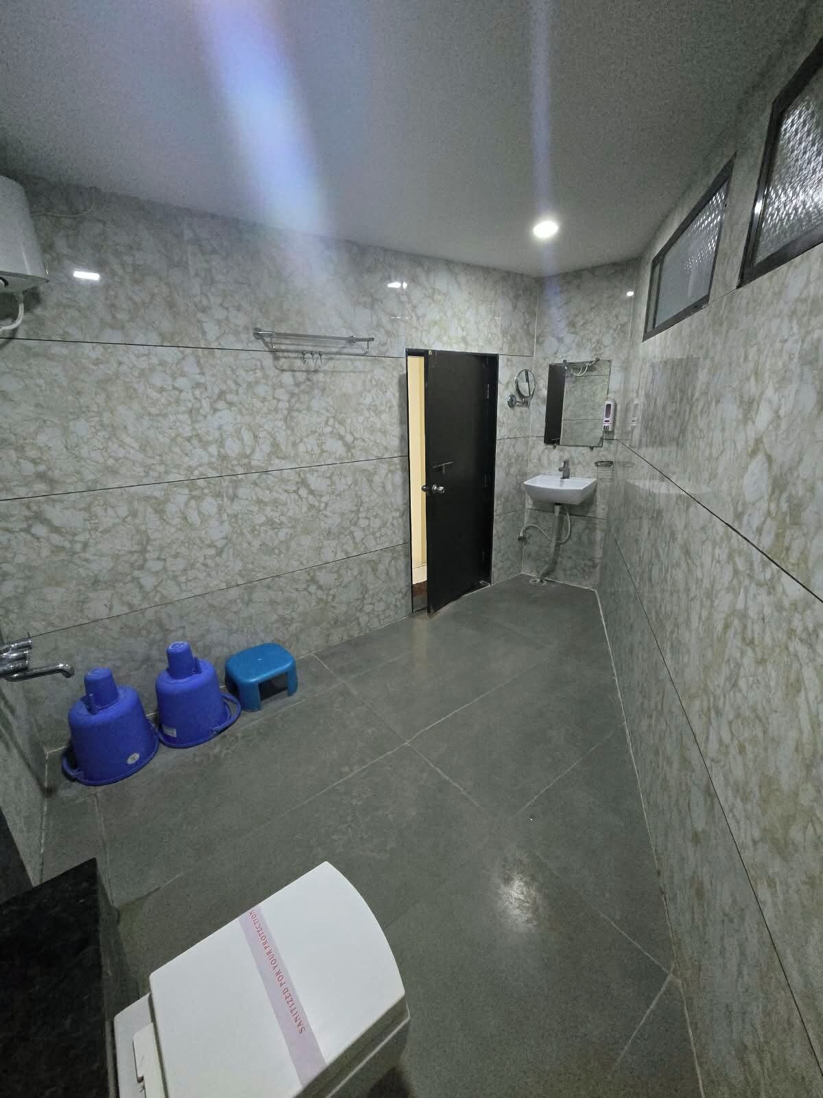 Un baño con pared de mármol, un lavamanos, un espejo y una puerta.
