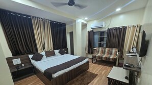 A bedroom with a bed, nightstand, TV, and a small desk. - Hotel Guru Inn (Nanded)