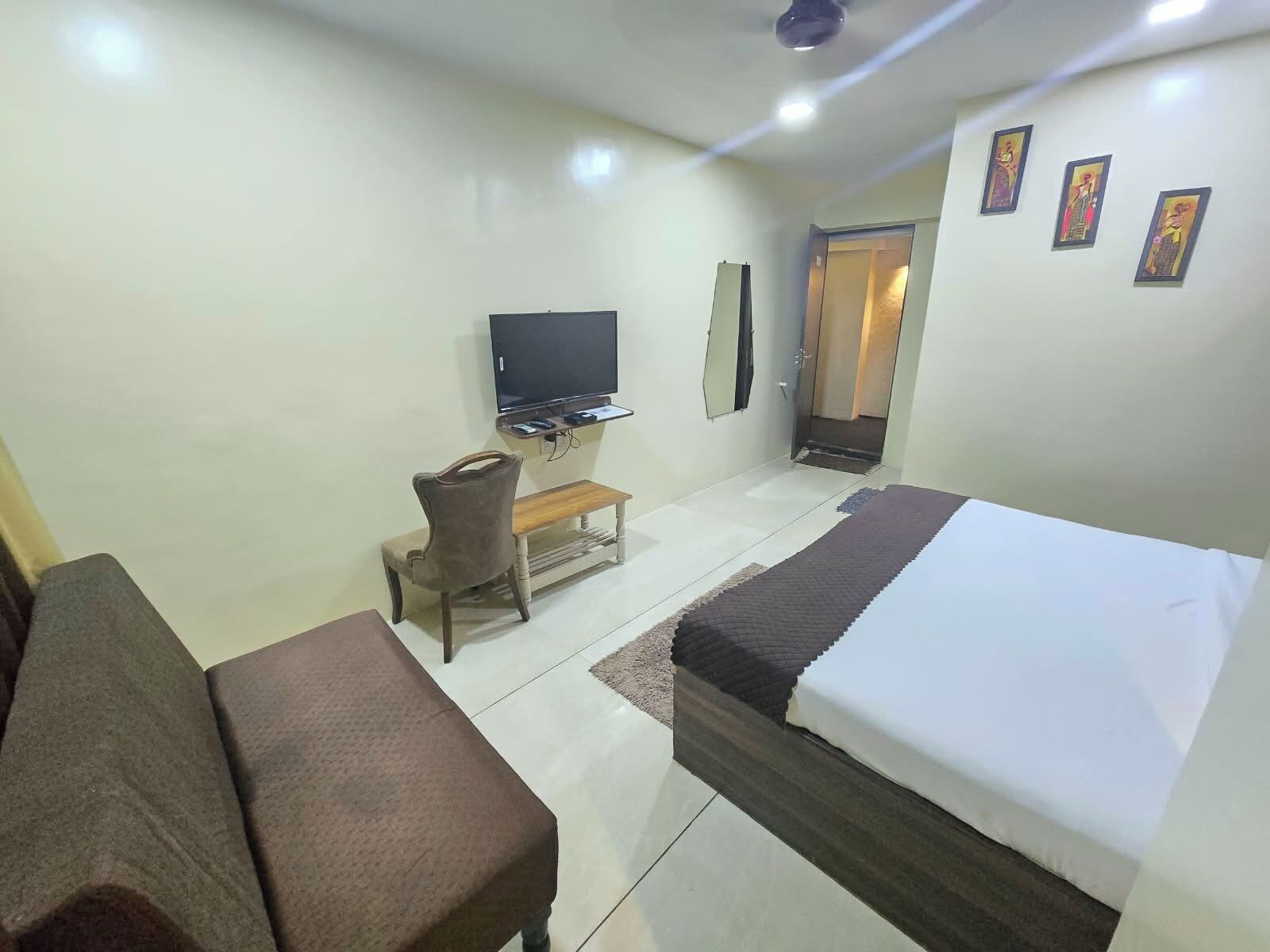 Una habitación de hotel con una cama, un sofá, un televisor y una mesita.
