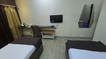 A hotel room with two beds, a desk with a chair, a television, and a bathroom with a mirror.