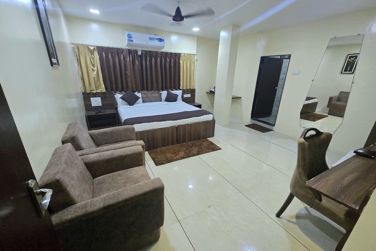 A hotel room with a bed, a desk, a chair, a mirror, and a ceiling fan.