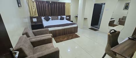 A hotel room with a bed, a desk, a chair, a mirror, and a ceiling fan.