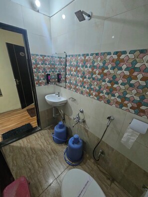 A bathroom with a tiled wall, a sink, a mirror, and a shower.