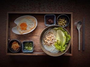 A tray with a bowl of noodle soup, a fried egg, and various condiments. - Yangshou Mountain Vista Courtyard (Guilin)