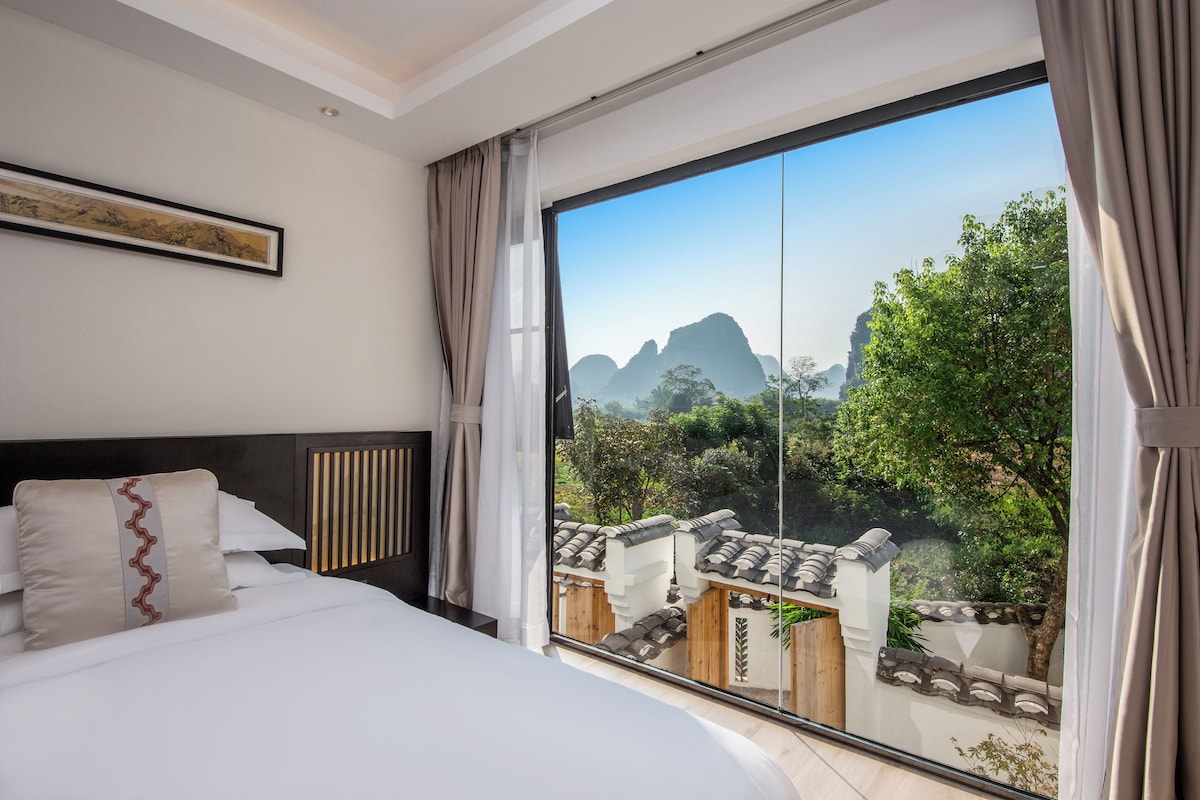 A hotel room with a large bed, a view of traditional architecture, and a balcony.