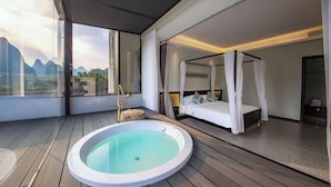 A modern bedroom with a four-poster bed, a separate bathroom with a hot tub, and a view of mountains through large windows. - Yangshou Mountain Vista Courtyard (Guilin)
