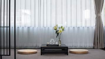 Una habitación con una mesa de centro negra, un florero con flores y un tapete tejido tradicional.
