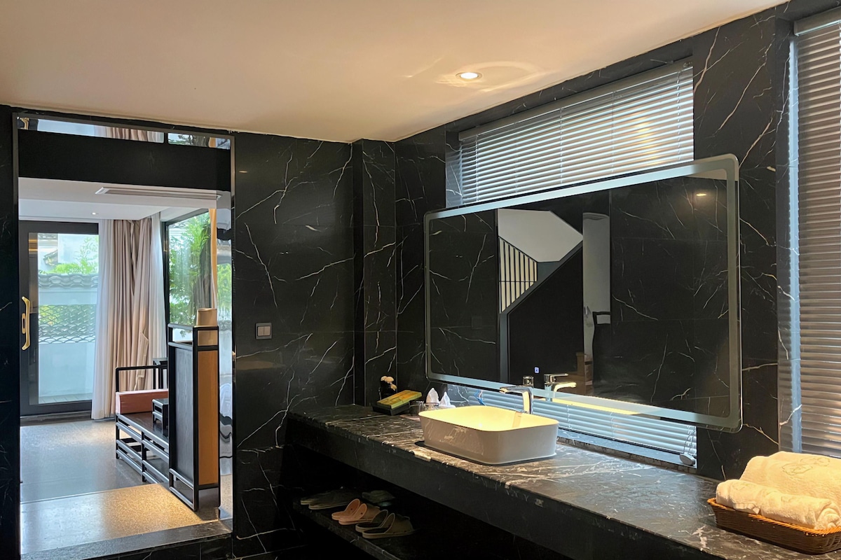 A modern bathroom with a large mirror, a sink, and a towel rack.