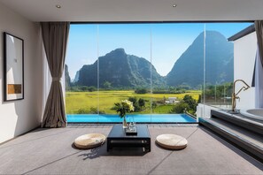Una habitación moderna con un ventanal grande, vistas a una montaña y una piscina.