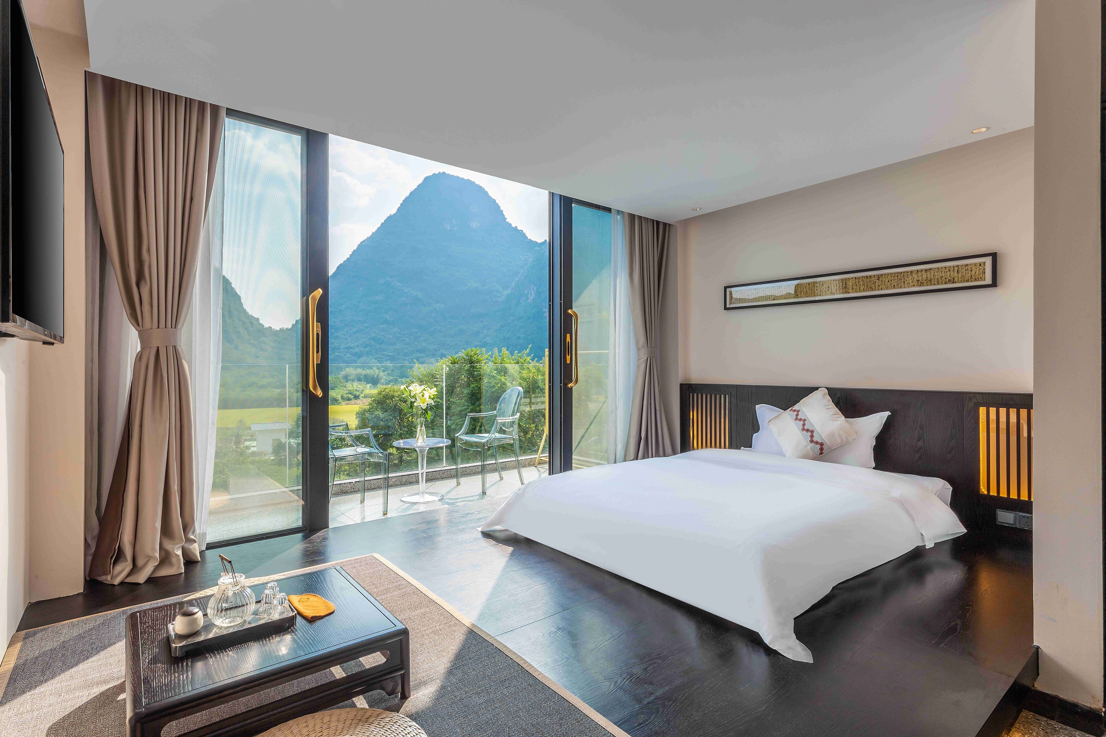 Habitación de hotel con una cama grande, una mesita de café y vistas a la montaña.
