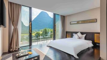 Habitación de hotel con una cama grande, una mesita de café y vistas a la montaña.