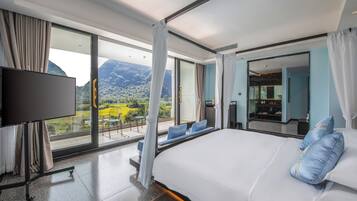 A hotel room with a large bed, a TV, and a balcony with a mountain view.
