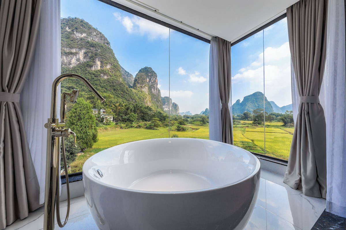 A large bathtub in a room with a view of a mountainous landscape.