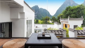 Ein Balkon mit einem Tisch für zwei Personen, mit Blick auf eine gebirgige Landschaft und traditionelle Architektur.