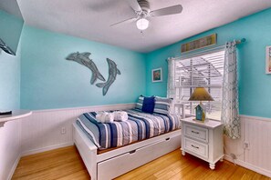 A bedroom with a bed, a nightstand, a window with curtains, a ceiling fan, and wall art. - Splash House at Indian Ridge | 4BR/2BA Kissimmee | Pool, Game Room (Kissimmee)