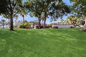 A well-maintained grassy area with trees and benches, suggesting a park-like setting. - Splash House at Indian Ridge | 4BR/2BA Kissimmee | Pool, Game Room (Kissimmee)