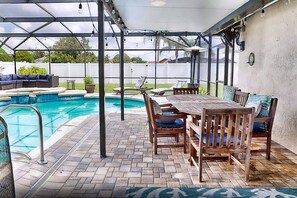 A covered outdoor area with a pool, patio furniture, and a view of the backyard. - Splash House at Indian Ridge | 4BR/2BA Kissimmee | Pool, Game Room (Kissimmee)