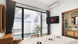 Hotellihuone, jossa on sänky, työpöytä, seinälle asennettu televisio sekä kylpyhuone, jossa on peili ja pesuallas.