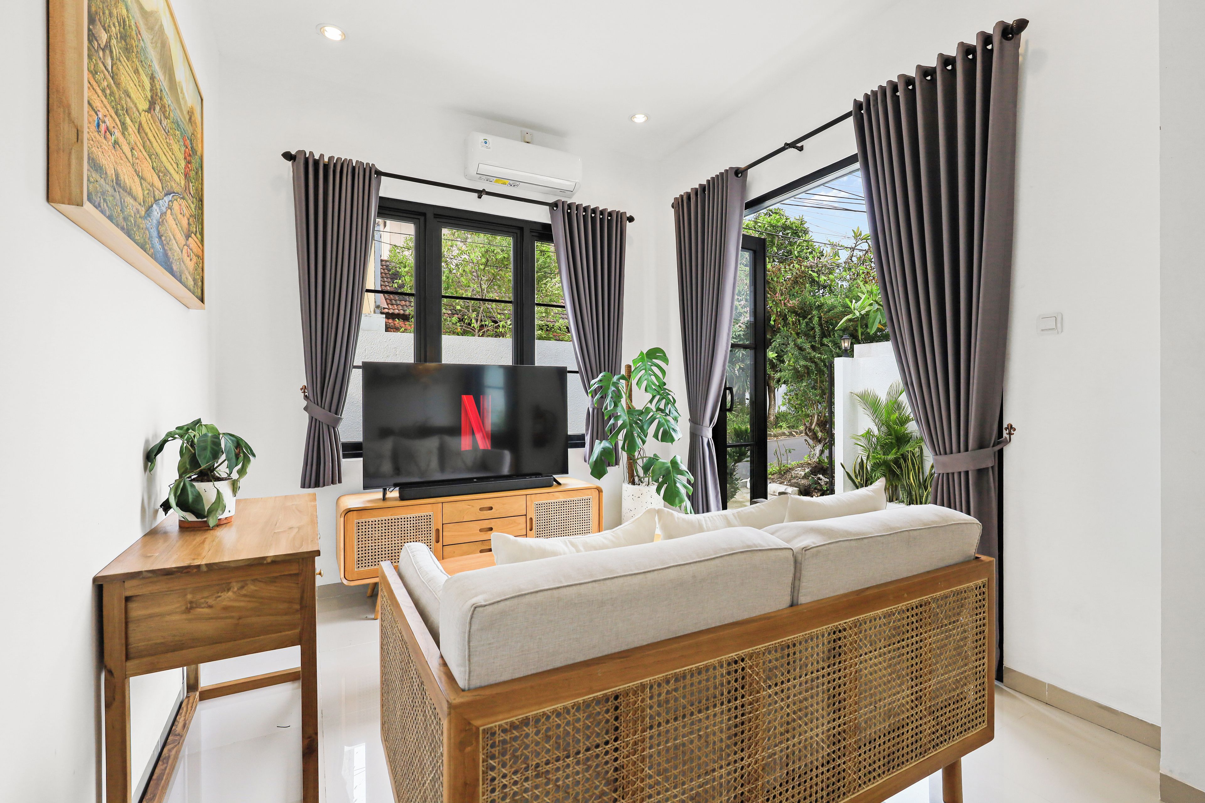 Een moderne woonkamer met een televisie, bank, eettafel en potplanten.