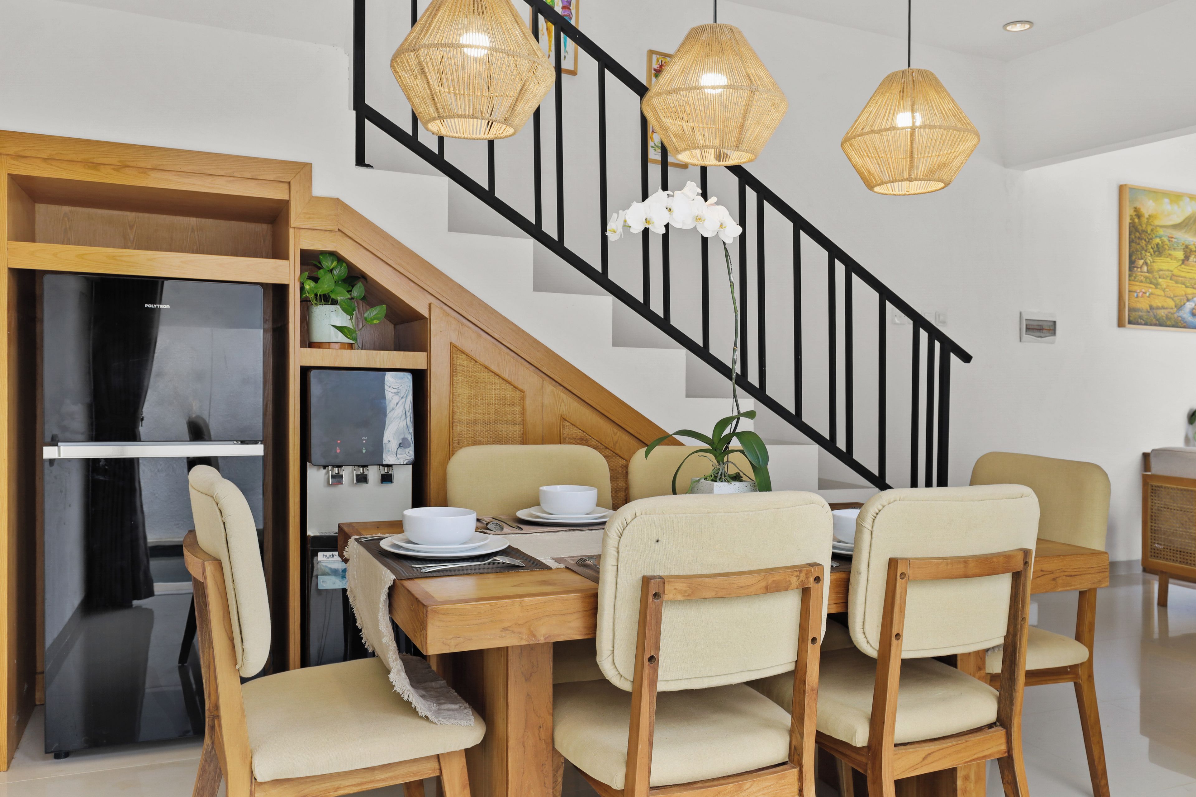 Un coin repas avec une table en bois, quatre chaises et un escalier noir.