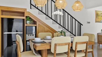 Un coin repas avec une table en bois, quatre chaises et un escalier noir.