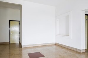 Quarto com soalho em mosaicos, uma porta e uma parede com painel embutido.