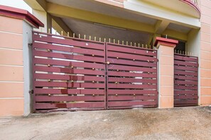 Une entrée fermée par un portail en métal et un chemin en béton menant à un bâtiment.